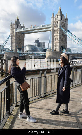 Touristen machen Fotos an der Tower Bridge, da kaltes und dennoch helles Herbstwetter Touristen und Londoner anzieht, die Sehenswürdigkeiten im Zentrum Londons zu erkunden. Stockfoto