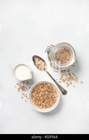 Zutaten für ein gesundes Frühstück: Müsli und Milch auf einem weißen konkreten Hintergrund. Ansicht von oben Stockfoto