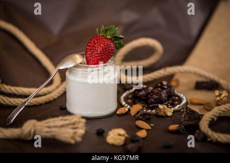 Dessert Zusammensetzung coconut Creme mit Erdbeeren und Muttern auf braunem Grund mit dekorativer Spitze und Schokolade Stockfoto