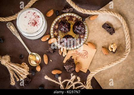 Dessert Zusammensetzung coconut Creme mit Erdbeeren und Muttern auf braunem Grund mit dekorativer Spitze und Schokolade Stockfoto