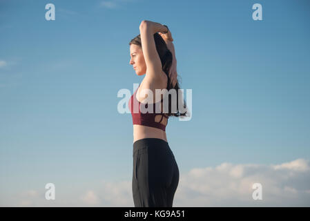 Sportliche Frau das Tragen eines Sport-BH, der eine Arm strecken außerhalb fit halten. Stockfoto