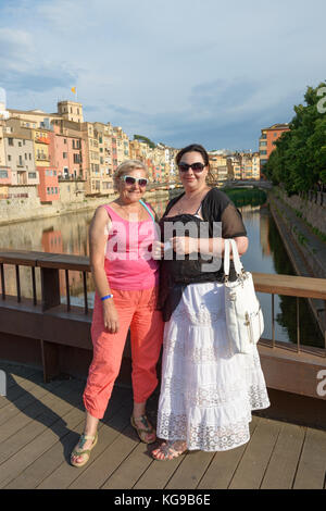 Zwei Frauen, Mutter und Tochter auf sant feliu Brücke auf dem Hintergrund der berühmten bunten Häuser in Girona, Spanien. Stockfoto