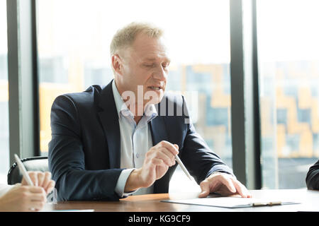 Ausgereifte Mann am Besprechungstisch im Büro und im Gespräch Stockfoto