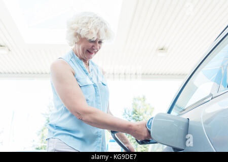 Active Senior lächelnde Frau beim Befüllen des Gastanks Ihrer Stockfoto