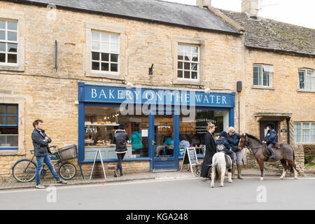 Bourton auf dem Wasser, Gloucestershire, England, UK-Kinder auf Ponys außerhalb Handwerker Bäckerei in der hübschen Cotswold Village Stockfoto