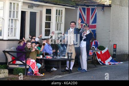 Zuschauer in Vintage fancy dress Wave auf die Wettbewerber, wie sie fahren durch Cuckfield Dorf während der London nach Brighton Veteran Car Run. 05. November 2017 Stockfoto