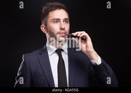 Bild von ernsthaften Geschäftsmann stehend mit vaping Gerät Stockfoto