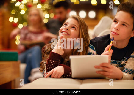 Nette Jungen und Mädchen liegt und schreibt Brief für weihnachten santa claus Stockfoto