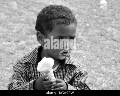 Ein junger australischer Einheimischer, der einen schmelzenden Eiskegel isst Stockfoto