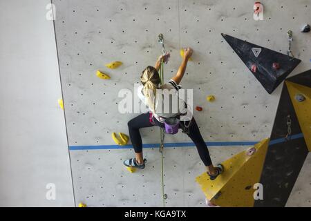 Junge Frau Skalierung Kletterwand in Höhe Ort Recreation Center in Canmore, Alberta, Kanada Stockfoto