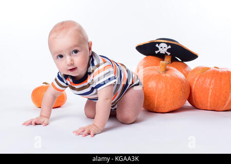 Schönes Baby in einem gestreiften Hemd auf einem weißen Hintergrund Kürbisse Stockfoto