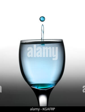 Farbige Wassertropfen spritzen in Kristall Glas Wein Stockfoto