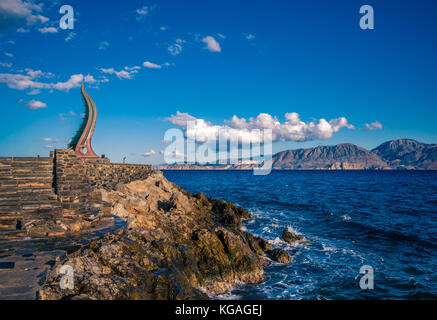 Der amalthea Horn Skulptur am Hafen von Agios Nikolaos entfernt. kretischen Berge im Hintergrund. Stockfoto