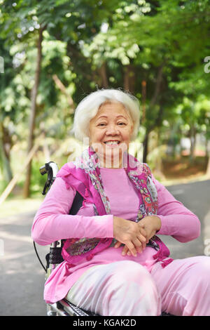 Portrait von asiatischen Senior Frau sitzt auf einem Rollstuhl im Freien Stockfoto