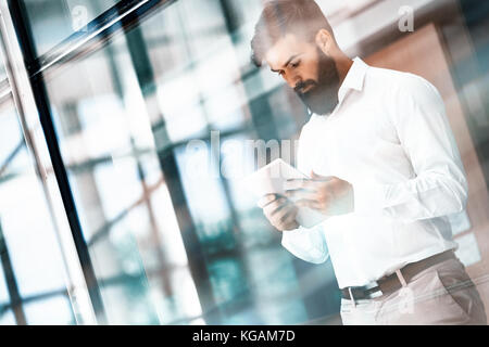 Hübscher junger Geschäftsmann über seine digitalen Tablet Stockfoto