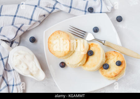 Hausgemachten Quark Pfannkuchen mit Sour creme mit Beeren und saure Sahne. Gesundes Müsli frühstück Konzept. Stockfoto