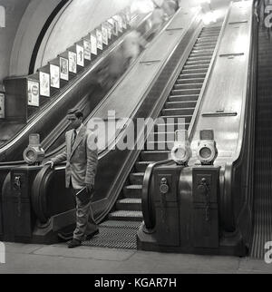 Anfang 1950s, historisches Bild, das einen gut gekleideten männlichen Besucher aus Übersee in England zeigt, der die Rolltreppe auf seiner Reise mit der Londoner U-Bahn, London, England, Großbritannien, verlassen hat. Stockfoto