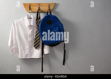 Schuluniform und Schultasche hängen an Haken gegen die Wand Stockfoto