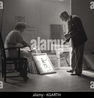 1950er Jahre, historische Bild zeigt einen Mann und eine Frau entscheiden, welche Bilder für eine Galerie anzeigen auszuwählen. Stockfoto
