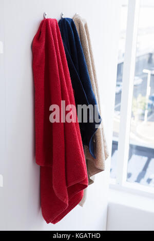 Bunte Handtücher hängen an Haken gegen die Wand Stockfoto