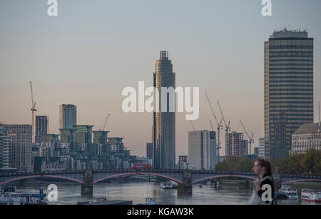 St George Wharf Tower bei Sonnenaufgang hinter der Vauxhall Bridge mit Millbank Tower skyscraper Rechts, Fußgänger im Vordergrund. London, Großbritannien Stockfoto