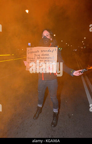 Weibchen mit Flare und Nachricht. Millionen Maske März Anonyme für die Stimmlosen Protestdemonstration durch London auf Guy Fawkes Nacht, November 5. Stockfoto