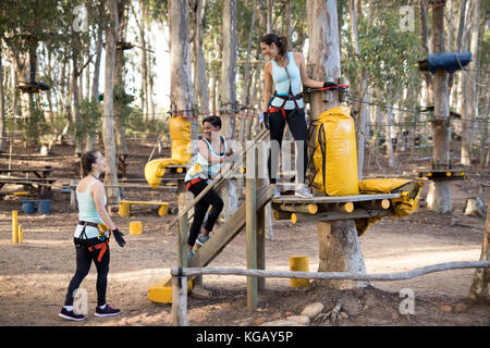 Freunde vorbereiten für Zip Line im Wald an einem sonnigen Tag Stockfoto