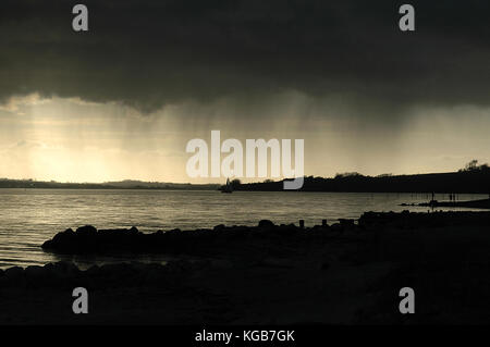 Dunklen Himmel mit dem Niederschlag, der Streifen über eine Landschaft mit Blick aufs Meer Stockfoto