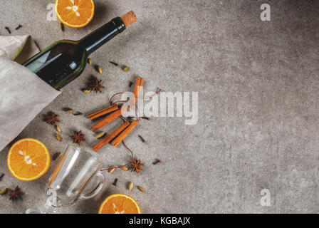Weihnachten heiße Getränke Rezepte, von Zutaten für Glühwein: Wein Flasche, Glas Tassen, Gewürze, orange. grauen Stein Hintergrund, Ansicht von oben Raum Stockfoto