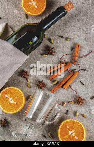 Weihnachten heiße Getränke Rezepte, von Zutaten für Glühwein: Wein Flasche, Glas Tassen, Gewürze, orange. grauen Stein Hintergrund, Ansicht von oben Raum Stockfoto