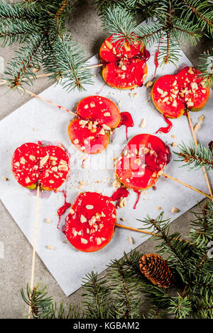 Ideen von Winter, Weihnachten behandelt. Süßigkeiten für Kinder. Schokolade Apfelscheiben rot Karamell und Muttern. grauen Stein Hintergrund, mit Weihnachtsbaum Bra Stockfoto