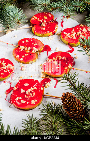 Ideen von Winter, Weihnachten behandelt. Süßigkeiten für Kinder. Schokolade Apfelscheiben rot Karamell und Muttern. grauen Stein Hintergrund, mit Weihnachtsbaum Bra Stockfoto