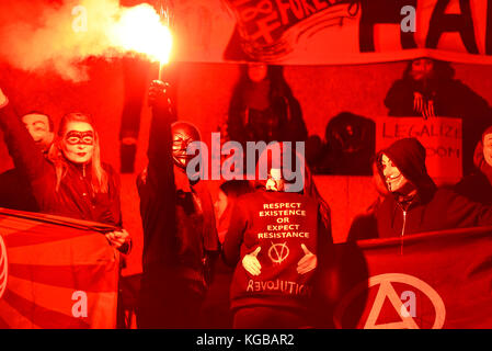 Flare an Millionen Maske März Anonyme für die Stimmlosen Protestdemonstration durch London entzündet sich auf Guy Fawkes Nacht, 5. November. Rotes Leuchten Stockfoto