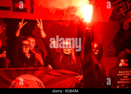 Flare an Millionen Maske März Anonyme für die Stimmlosen Protestdemonstration durch London entzündet sich auf Guy Fawkes Nacht, 5. November. Rotes Leuchten Stockfoto