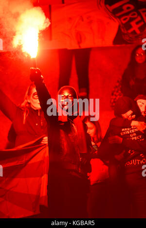 Flare an Millionen Maske März Anonyme für die Stimmlosen Protestdemonstration durch London entzündet sich auf Guy Fawkes Nacht, 5. November. Rotes Leuchten Stockfoto