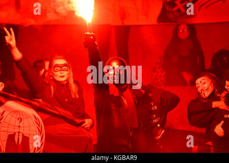 Flare an Millionen Maske März Anonyme für die Stimmlosen Protestdemonstration durch London entzündet sich auf Guy Fawkes Nacht, 5. November. Rotes Leuchten Stockfoto