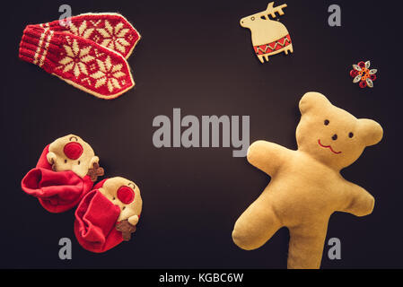 Baby Handschuhe, Stiefeletten und ein Teddybär auf Schwarz Stockfoto