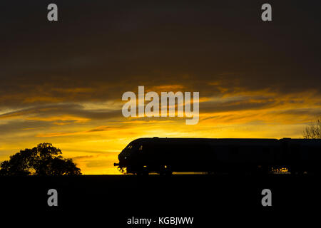 Warwick, Warwickshire, England, UK. 6. November 2017. Ein Chiltern Railways Service in London Marylebone ist bei Sonnenuntergang Silhouette, da es Ansätze Warwick Parkway Station. Credit: Colin Underhill/Alamy leben Nachrichten Stockfoto