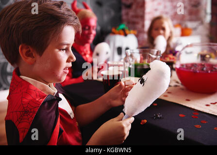 Junge in Vampir Kostüm essen eine Zuckerwatte Stockfoto