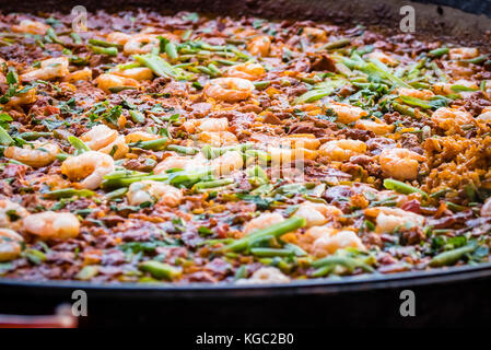 Paella Schüssel mit Garnelen, closeup. Bunte spanische Paella Reis im Topf mit Gemüse und Garnelen. Stockfoto