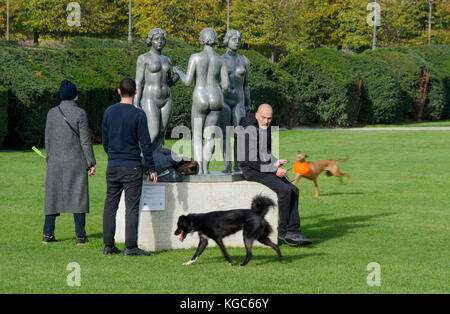 Paris, Frankreich. Jardin des Tuileries: Les Nymphes / Trois Grâces (drei Grazien) von Aristide Maillol, 1938. Mann mit Handy und Hundespaziergänger Stockfoto