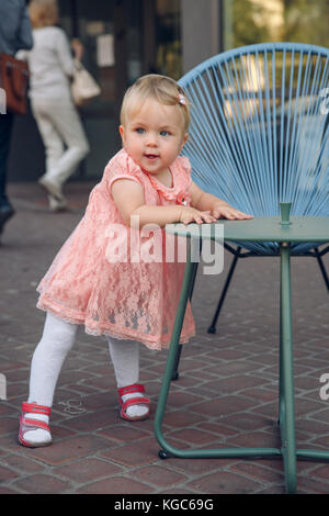 Die ersten Schritte Die ersten eigenständigen Schritte. Baby girl Walking im Park mit alten Stuhl unterstützen Stockfoto