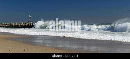 Große Wellen gegen diesen Steg mit seiner navigatorischen Rundumleuchte am Morgen nach einem starken Sturm bewegt sich an der Ostküste von New Jersey Stockfoto