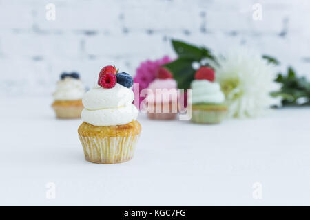 Verschiedene Cupcakes mit frischen Beeren Blumen und Blätter. weißen Hintergrund. Stockfoto