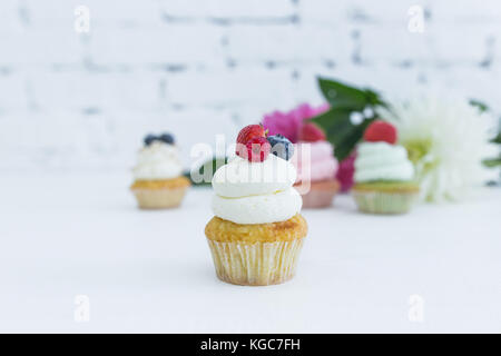 Verschiedene Cupcakes mit frischen Beeren Blumen und Blätter. weißen Hintergrund. Stockfoto