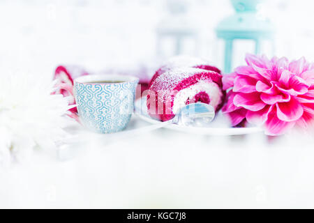 Eine Red Velvet Cake roll geschnitten bei einer Tasse Kaffee oder Tee und Blumen. weißen Hintergrund. Stockfoto