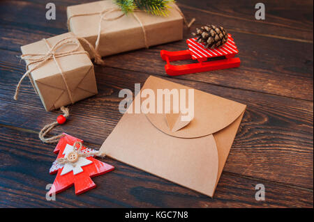 Mockup Weihnachten leere Karte, Umschlag mit Geschenkboxen, Weihnachten Elemente auf einer hölzernen Hintergrund Stockfoto