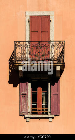 Äußere des klassischen französischen Wohnung Balkon und Fenster mit offenen und geschlossenen roten verfallenen Fensterläden Stockfoto