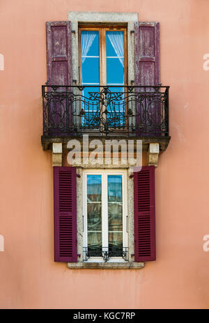 Fassade Fassade des klassischen französischen Apartment Gebäude eiserne Geländer Balkon und Fenster mit roten verfallenen Fensterläden Stockfoto