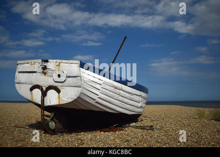 Alte blaue und weiße Fischerboot auf einem Kieselstrand aufgegeben mit einem blauen Himmel Hintergrund in Aldeburgh, Suffolk, Großbritannien Stockfoto